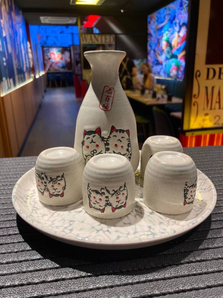 foto de una jarra de sake con los chupitos que tienen dibujos de gatitos en el estilo kawaii